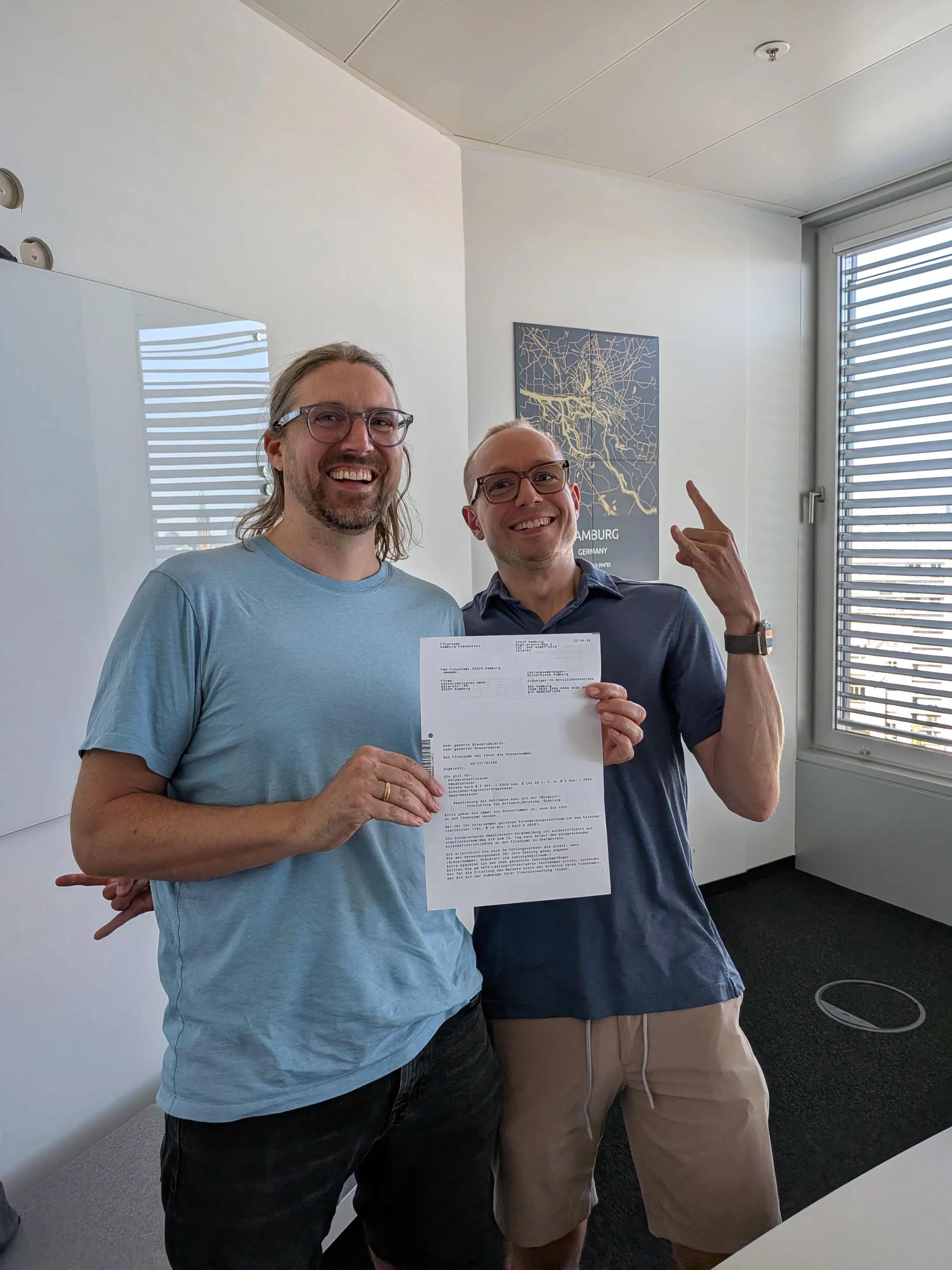 Two founders holding the Steuernummer letter, laughing